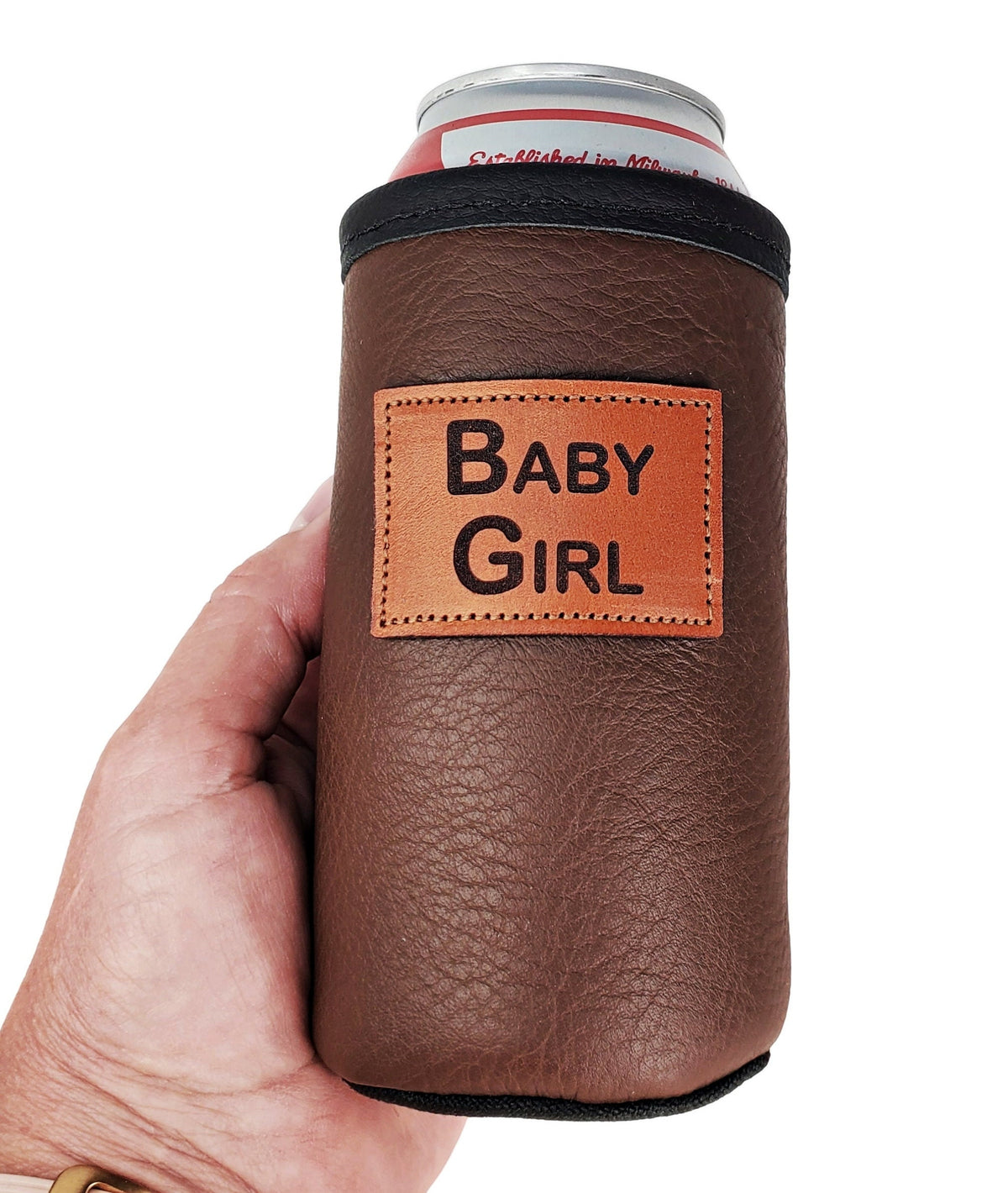 Hand holding a brown leather tall boy can cooler personalized with a Baby Girl patch