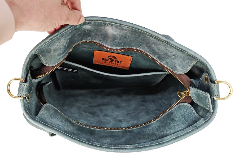 Top-down view inside sage Madison leather tote showing unlined interior, zipper, slip pocket, and brass D-rings