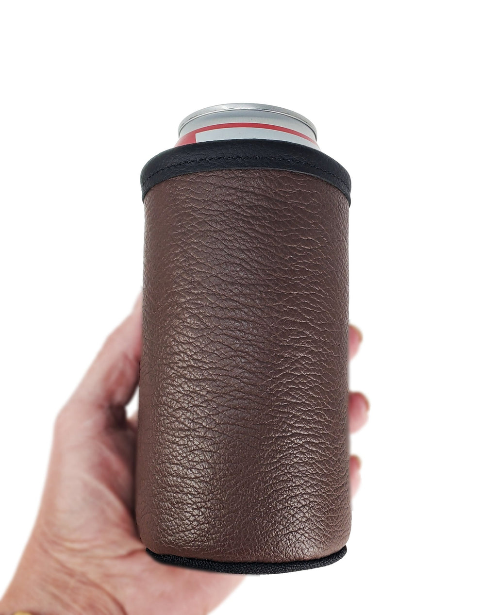 Brown smooth leather 16oz tall boy can cooler with black trim, held in one hand against a white background