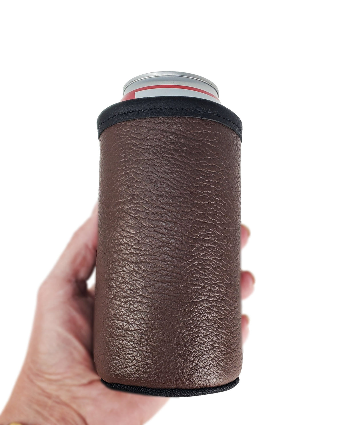 Brown smooth leather 16oz tall boy can cooler with black trim, held in one hand against a white background