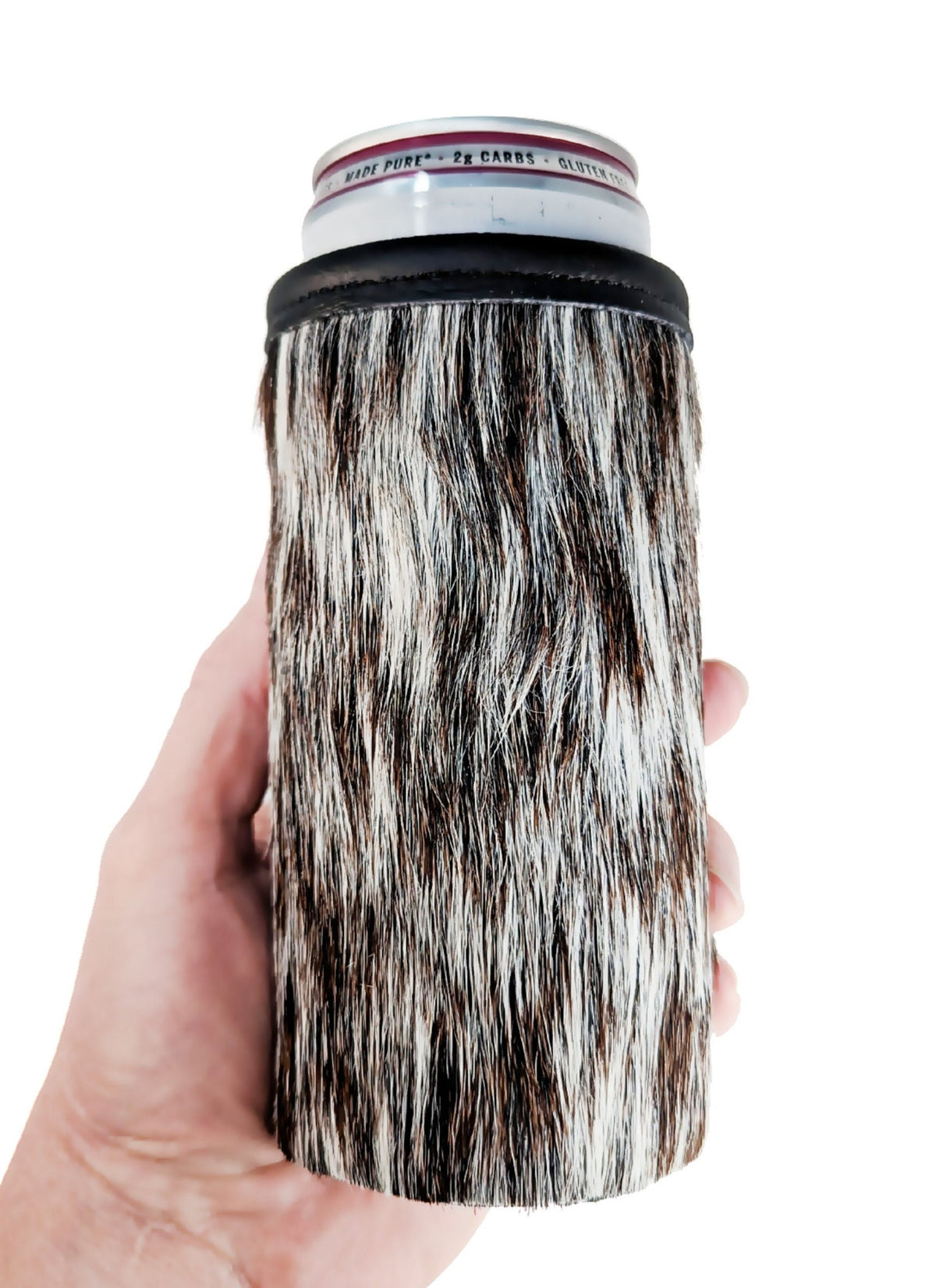 Hand holding a black and white speckled hair-on cowhide skinny can holder with a beverage can inside