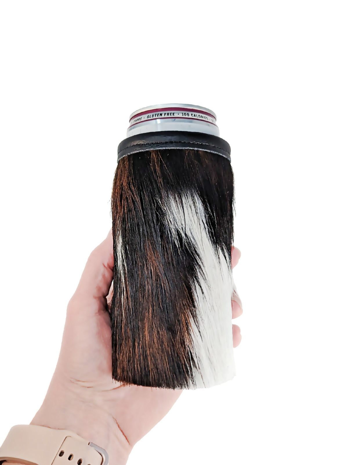 Hand holding a 12oz slim can cooler made from black, brown and white natural hair-on cowhide