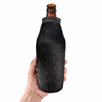 Black cowhide beer bottle holder shown in hand for scale