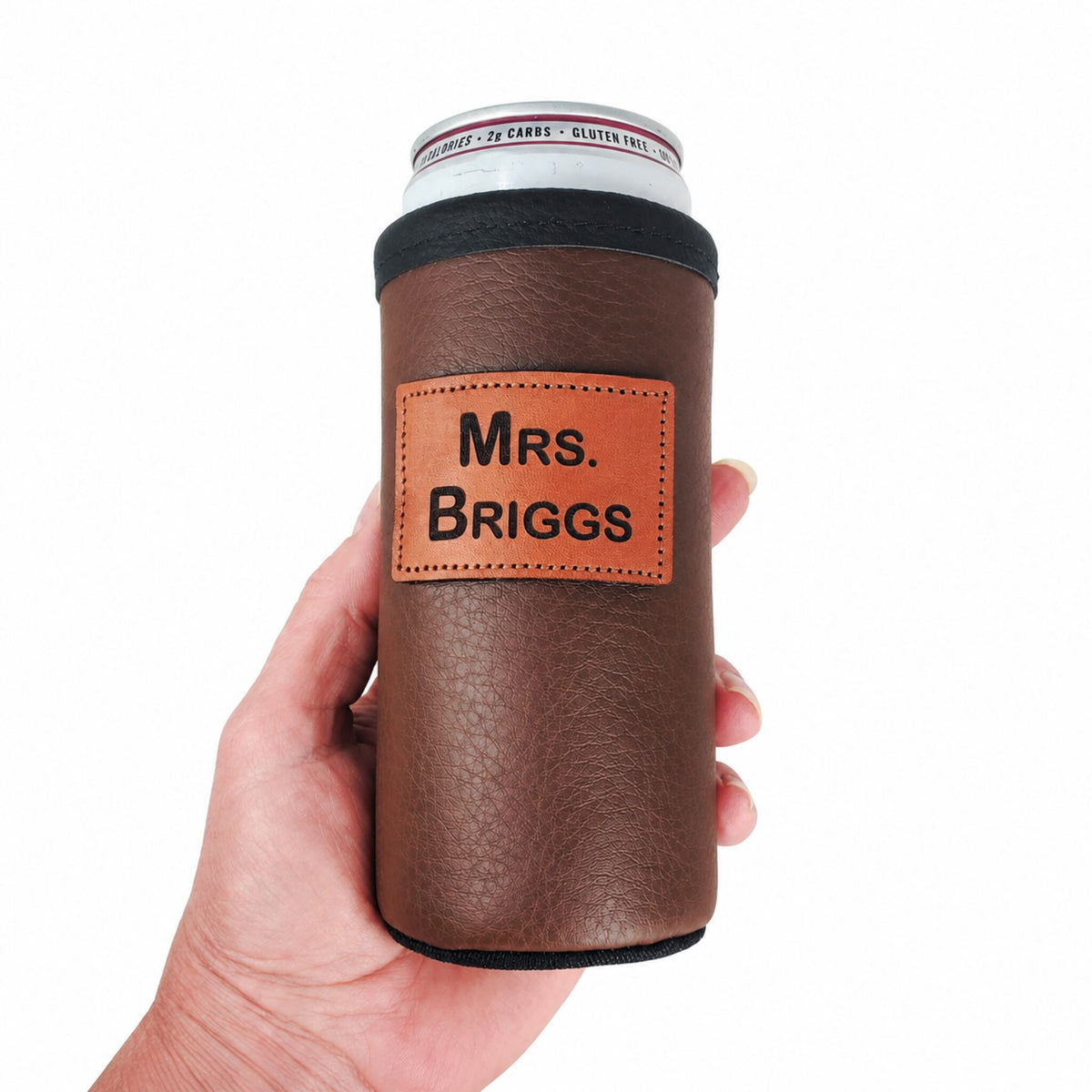 Brown personalized leather slim can holder shown in a hand for scale