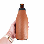 Hand holding a brown leather beer bottle holder on a standard long-neck bottle