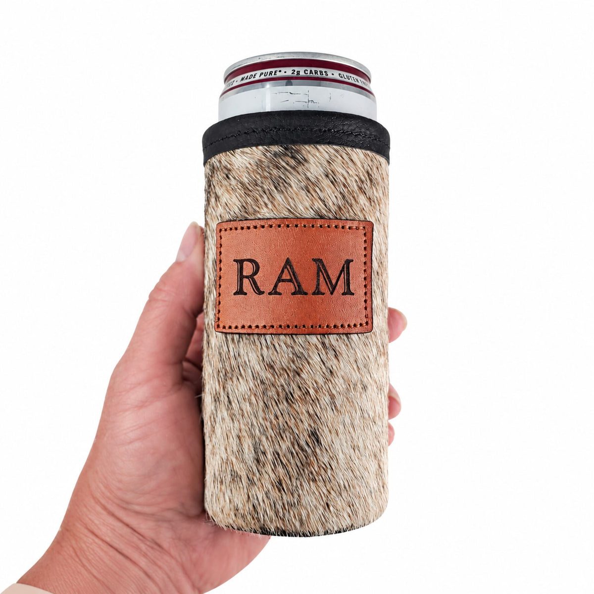 Light brindle cowhide slim can holder personalized with the initials RAM, shown in hand